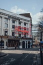 Woman walking past Mousetrap neon sign on the facade of St Martins Theatre, London, UK