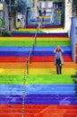 Woman is walking in the rainbow-colored stairs