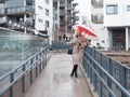 Woman walking rainy street with red umbrella