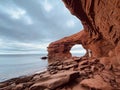 Woman walking on the red rocks at Cavendish Beach under cloudy sky, Prince Edward Island, Canada Royalty Free Stock Photo