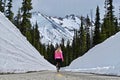 North Cascades Mountains with snow and woman walking on the road with snow walls.