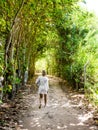Woman walking in rustic pathway between trees on a sunny day