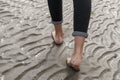 Woman walking on sandy beach leaving footprints in the beach