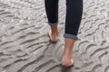 Woman walking on sandy beach leaving footprints in the beach