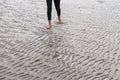 Woman walking on sandy beach leaving footprints in the beach