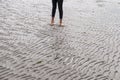 Woman walking on sandy beach leaving footprints in the beach