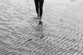 Woman walking on sandy beach leaving footprints in the beach