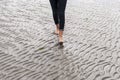 Woman walking on sandy beach leaving footprints in the beach