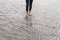 Woman walking on sandy beach leaving footprints in the beach