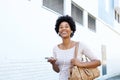 Woman walking on sidewalk with mp3 player and purse Royalty Free Stock Photo