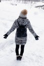 Woman walking in snow in winter clothes. Rear view of girl walking in snowy forest