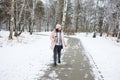 Woman walking on a snowy path in winter with a cup of drink in a forest setting Royalty Free Stock Photo