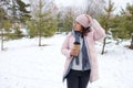 Woman walking on a snowy path in winter with a cup of drink in a forest setting Royalty Free Stock Photo