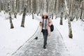 Woman walking on a snowy path in winter with a cup of drink in a forest setting Royalty Free Stock Photo