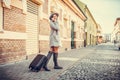 Woman walking through the street with suitcase while talking on Royalty Free Stock Photo