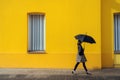 Woman walking on the street with umbrella in front of yellow building. Generative AI Royalty Free Stock Photo