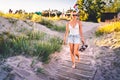 Woman walking in summer on beach boardwalk at sunset. Outdoor nature portrait of happy pretty girl enjoying life and summertime. Royalty Free Stock Photo