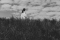 Woman walking in the tall grass on a windy day, alone, keeping distance from people