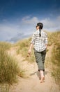 Woman walking to beach in sand dunes