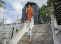 Woman walking toward huge ancient statue of Buddha in the yard of temple Royalty Free Stock Photo