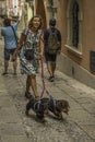 Woman walking two hound dogs in the old downtown historic district of Ortigia, Sicily