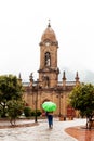 Woman walking with an umbrella at the beautiful central square aof the small town of Nobsa in a rainy day