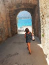 Woman walking under arch discovering fortress Spinalonga, Greece