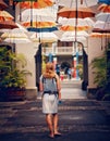 Woman walking under umbrellas in sunny tropical street