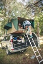 Woman walking up ladder to tent over car Royalty Free Stock Photo