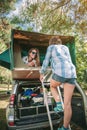 Woman walking up ladder to tent over car Royalty Free Stock Photo