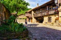 Woman walking through village of old houses with balconies with flowers. Barcena Mayor Santander