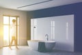 Woman walking in white and black bathroom with tub Royalty Free Stock Photo