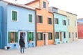 Woman walking a white dog near coloured houses in Burano, near Venice, Italy Royalty Free Stock Photo