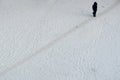 Woman walking in winter along the walkway in the courtyard covered snow, top view on a snow-covered field