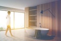 Woman walking in wooden bathroom with tub Royalty Free Stock Photo