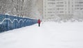 A woman walks along a fence to multi-storey building during snowfall in Moscow, Russia