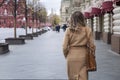 A woman walks along the Gum in Red Square. Elegant blonde in a beige coat. Back view