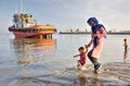 Woman walks along shore of Persian Gulf with her child. Royalty Free Stock Photo