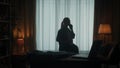 A woman walks around the room and speaks on the phone. A woman holds a blouse on a hanger in her hand. Dark silhouette