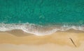 Woman walks on the beach along breaking waves leaving footprints on a sand, aerial view directly above