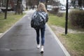 Woman walks through city. Girl in jeans on street. Backpack and jacket