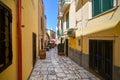 A woman walks down a colorful narrow alley towards a cafe in the Italian city of Brindisi Italy, in the Puglia region