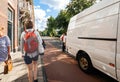 Woman walks on Dutch street near delivery man with parcels