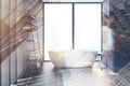 Woman walks in gray bathroom with tub and shelves