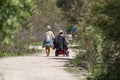 A woman walks with a man in wheelchair by nature