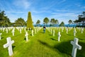 A woman walks through the Normandy American Cemetery and Memorial at Colleville-sur-Mer with rows of gravestones.