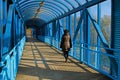 A woman walks on a overhead pedestrian bridge