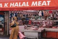 Woman walks past Halal Meat Store at Brixton Market, London, UK