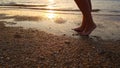 a woman walks on a sandy beach at sunset. warm sea water washes women's feet. Royalty Free Stock Photo