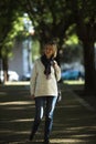 A woman walks in a shady green park.